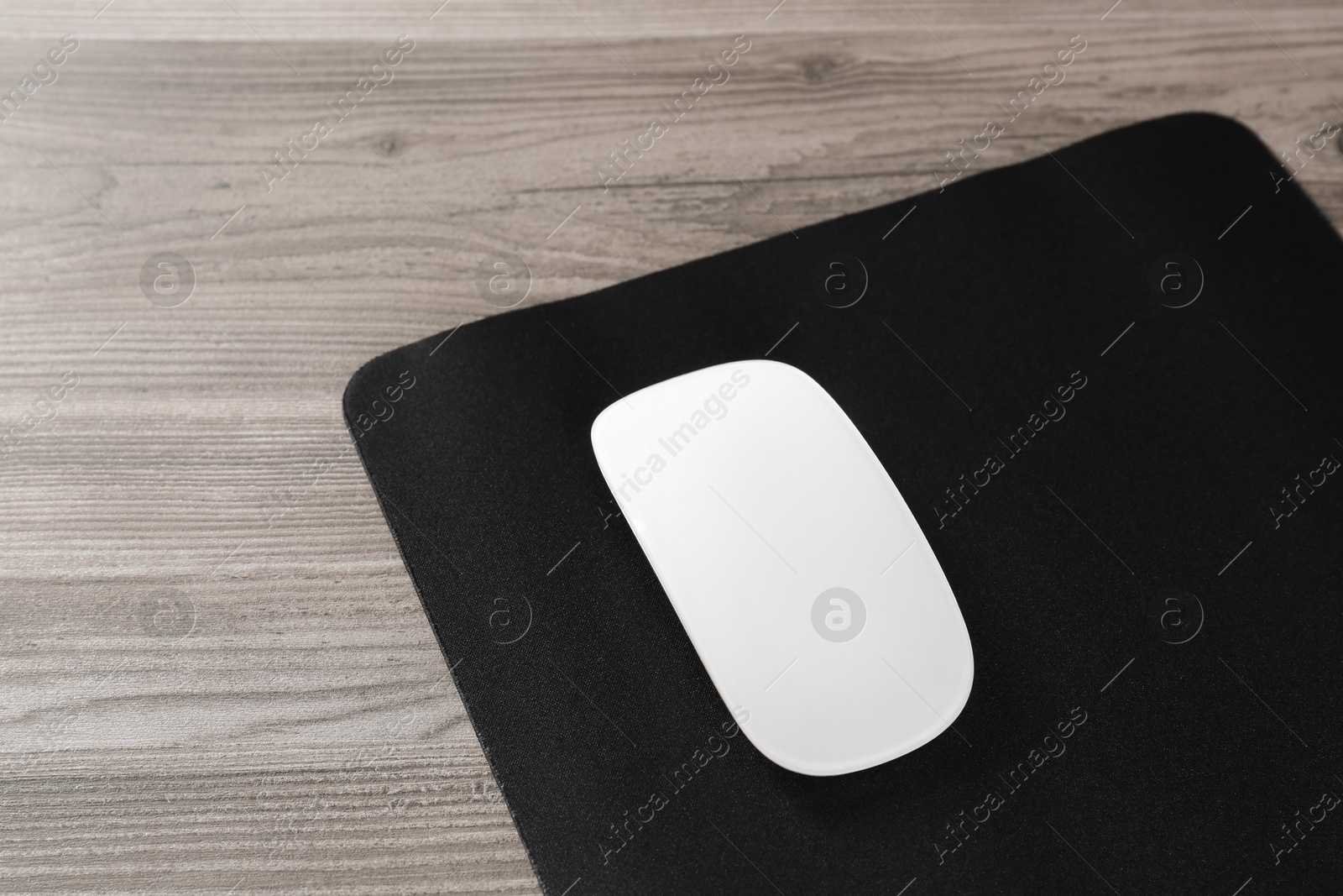 Photo of Wireless mouse and mousepad on wooden table