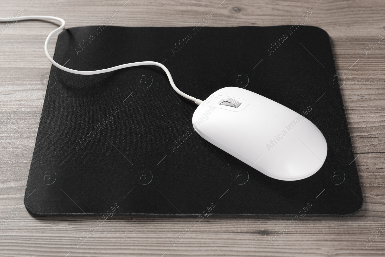 Photo of Wired mouse and mousepad on wooden table