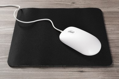 Wired mouse and mousepad on wooden table