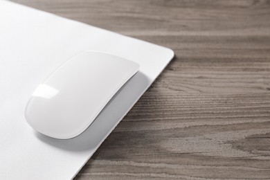 Wireless mouse and mousepad on wooden table, closeup. Space for text