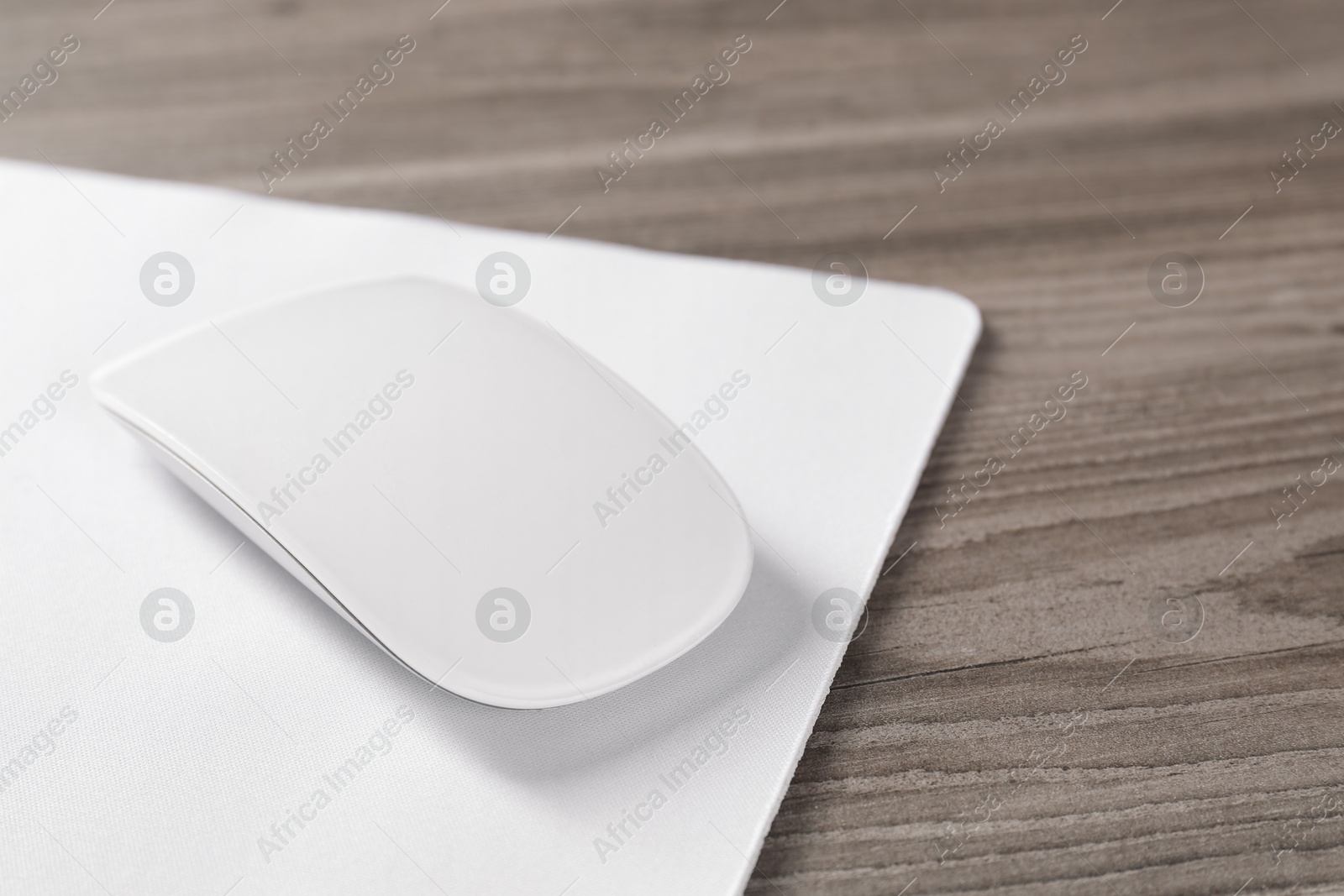 Photo of Wireless mouse and mousepad on wooden table, closeup. Space for text