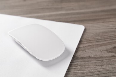 Wireless mouse and mousepad on wooden table, closeup. Space for text