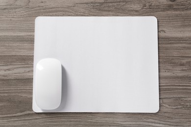 Photo of Wireless mouse and mousepad on wooden table, top view