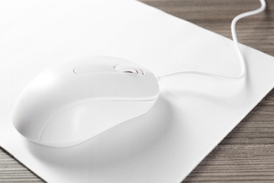 Wired mouse and mousepad on wooden table, closeup