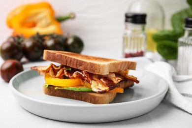 Photo of Tasty sandwich with bacon and bell pepper on white table, closeup