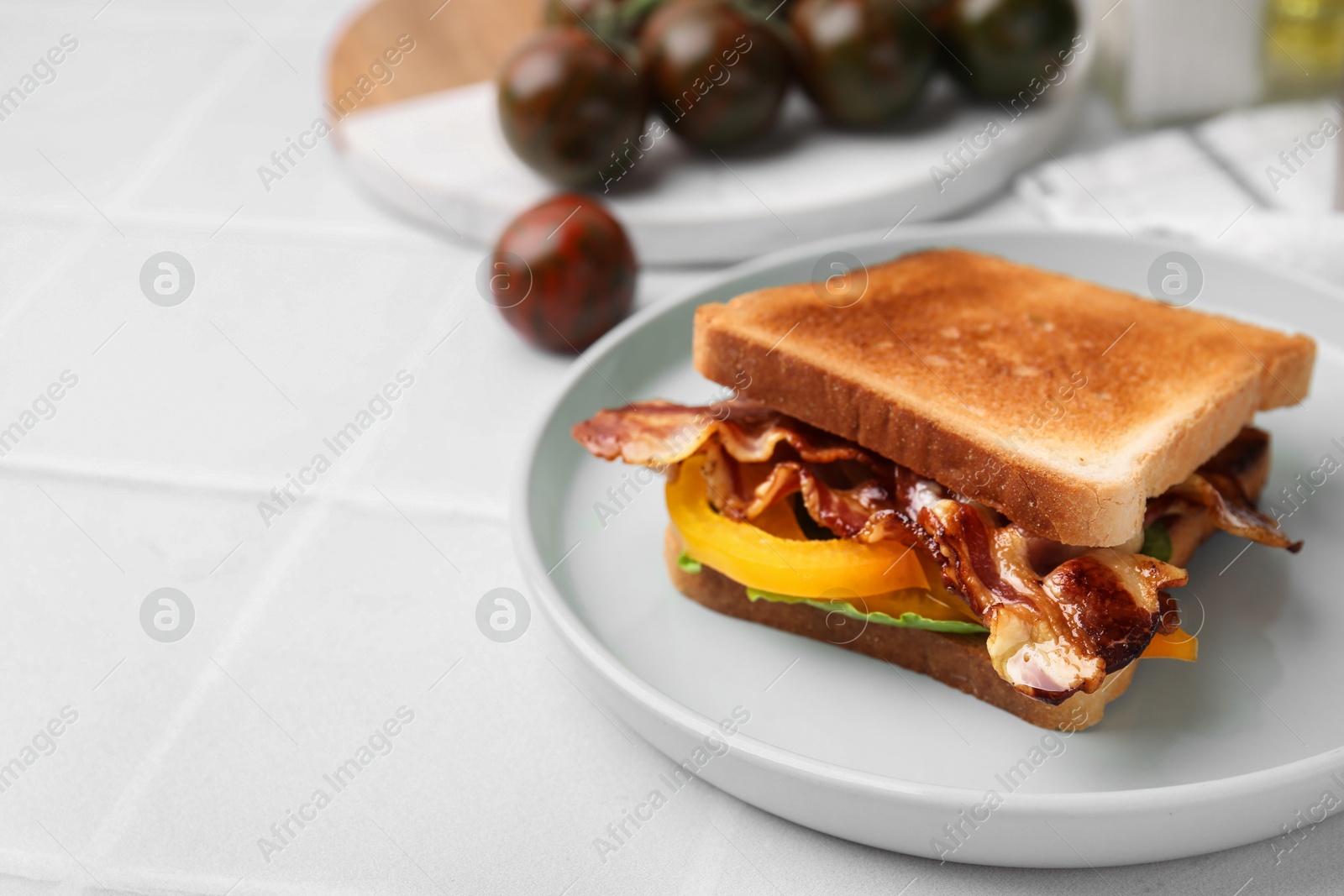 Photo of Tasty sandwich with bacon and bell pepper on white table, closeup. Space for text