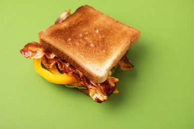 Photo of Tasty sandwich with bacon and bell pepper on green table