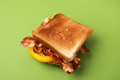 Photo of Tasty sandwich with bacon and bell pepper on green table