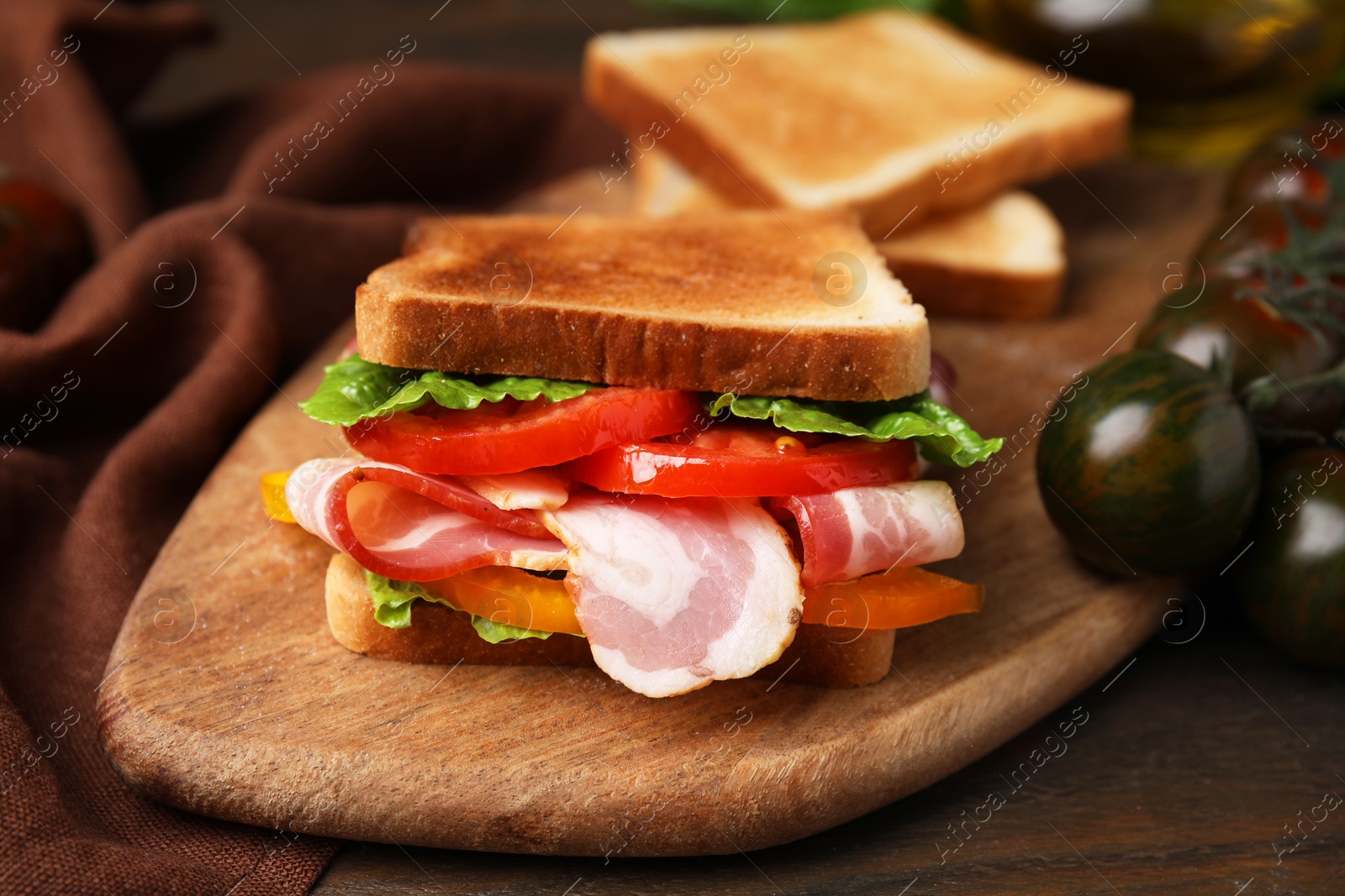 Photo of Tasty sandwich with bacon and tomato on wooden table, closeup