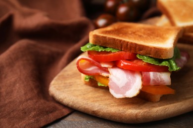 Photo of Tasty sandwich with bacon and tomato on wooden table, closeup