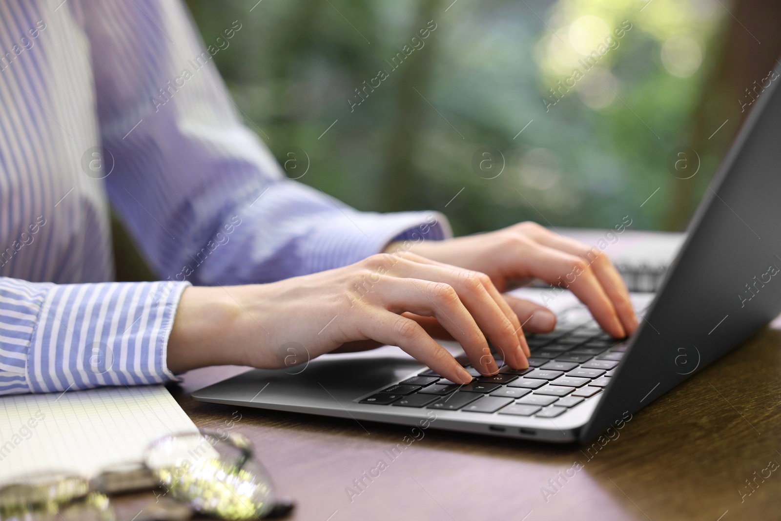 Photo of Businesswoman working with laptop at table outdoors, closeup. Remote job