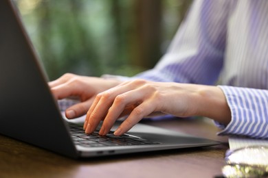 Photo of Businesswoman working with laptop at table outdoors, closeup. Remote job