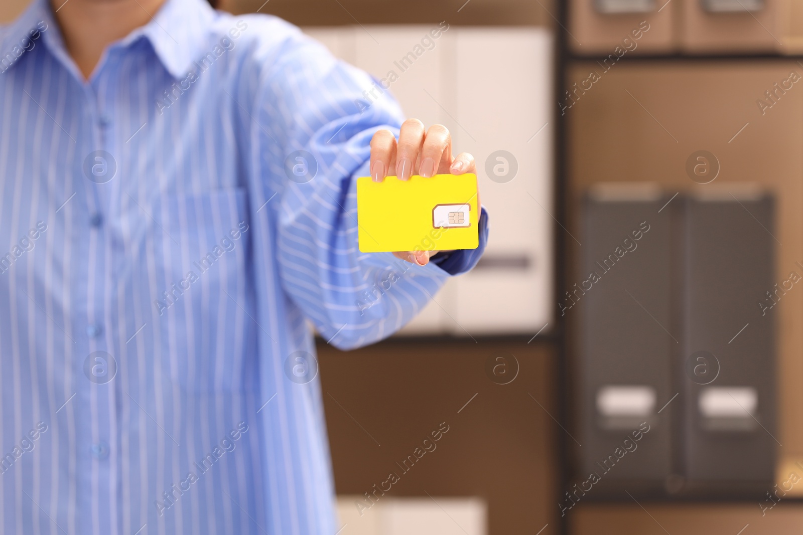 Photo of Woman holding SIM card indoors, closeup. Space for text