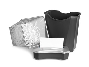 Shredder, metal basket and paper strips on white background