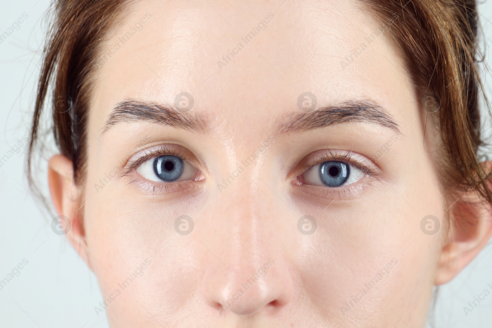 Photo of Woman with beautiful blue eyes on light background, closeup