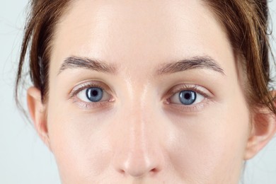 Photo of Woman with beautiful blue eyes on light background, closeup