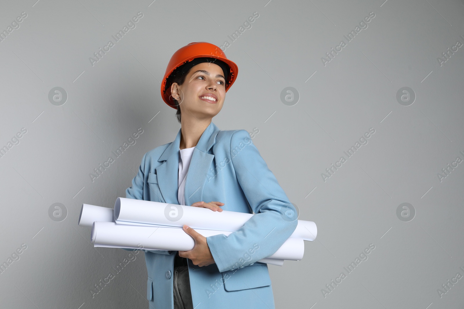 Photo of Engineer in hard hat with drafts on grey background