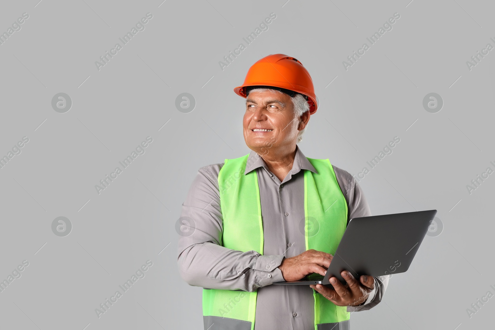 Photo of Engineer in hard hat with laptop on grey background, space for text