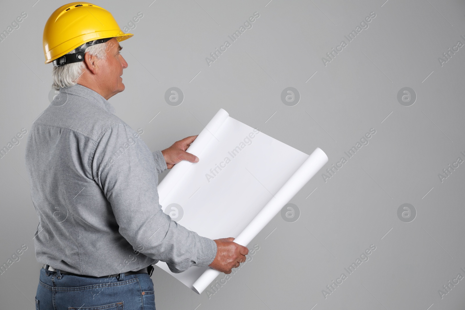 Photo of Engineer in hard hat with draft on grey background, space for text