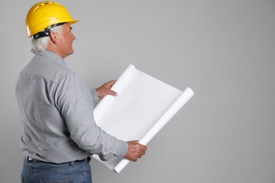 Photo of Engineer in hard hat with draft on grey background, space for text