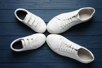 Photo of Big and small shoes on blue wooden table, top view