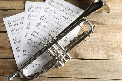 Photo of Trumpet and music sheets on wooden table, top view