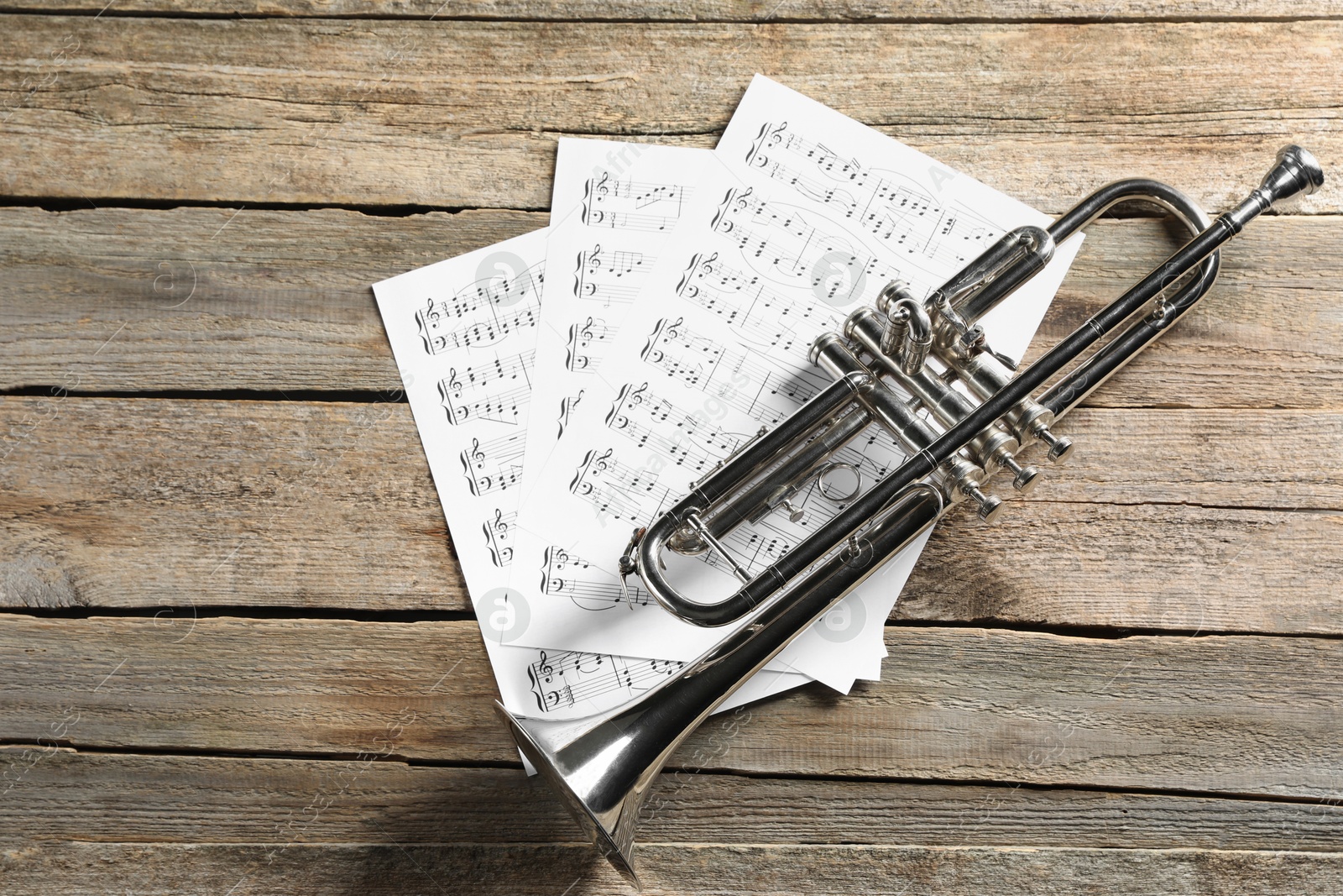 Photo of Trumpet and music sheets on wooden table, top view