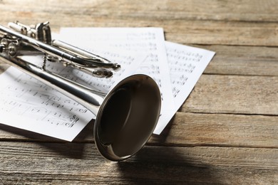 Trumpet and music sheets on wooden table, closeup