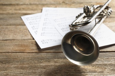 Photo of Trumpet and music sheets on wooden table, closeup