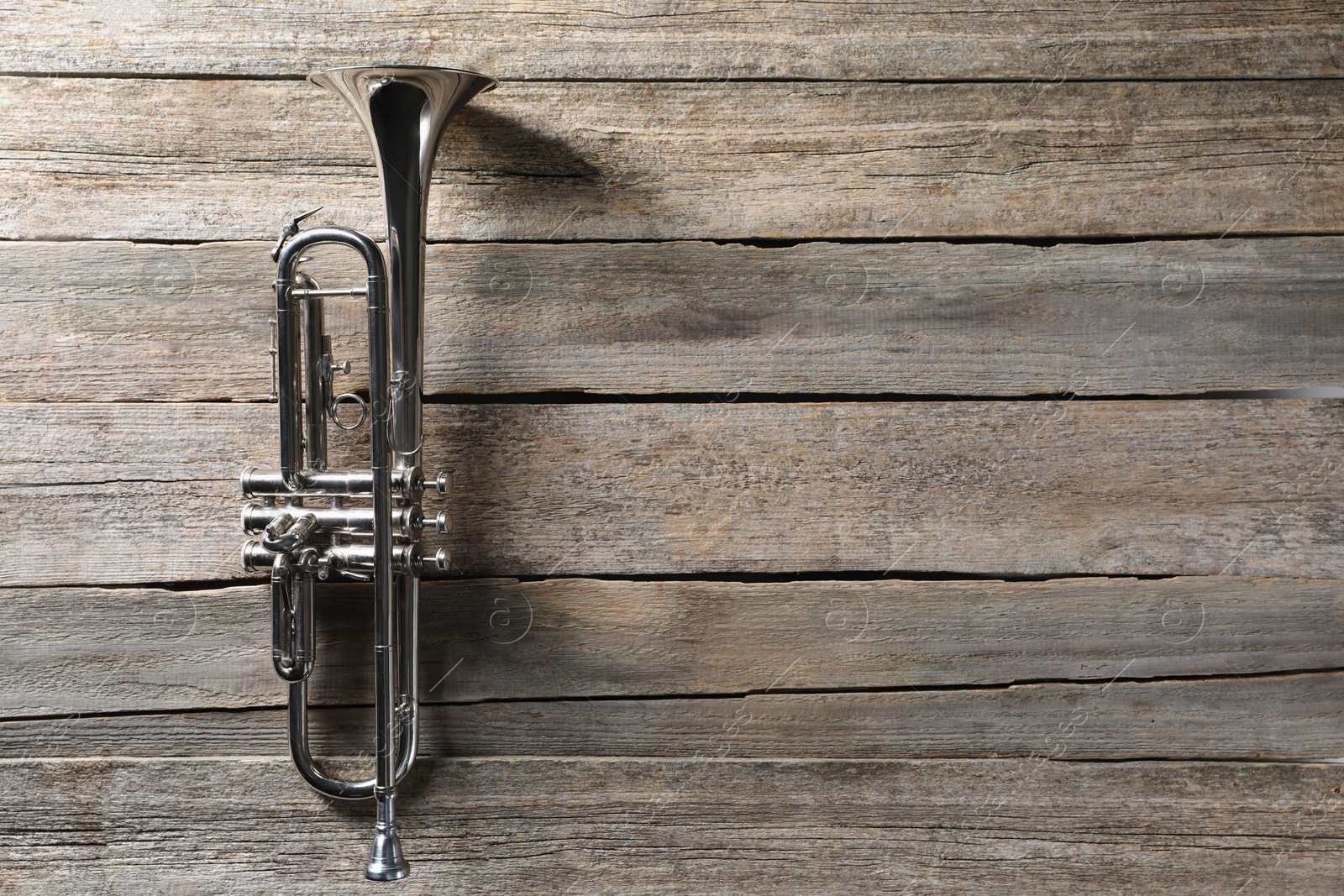 Photo of Trumpet on wooden table, top view. Space for text