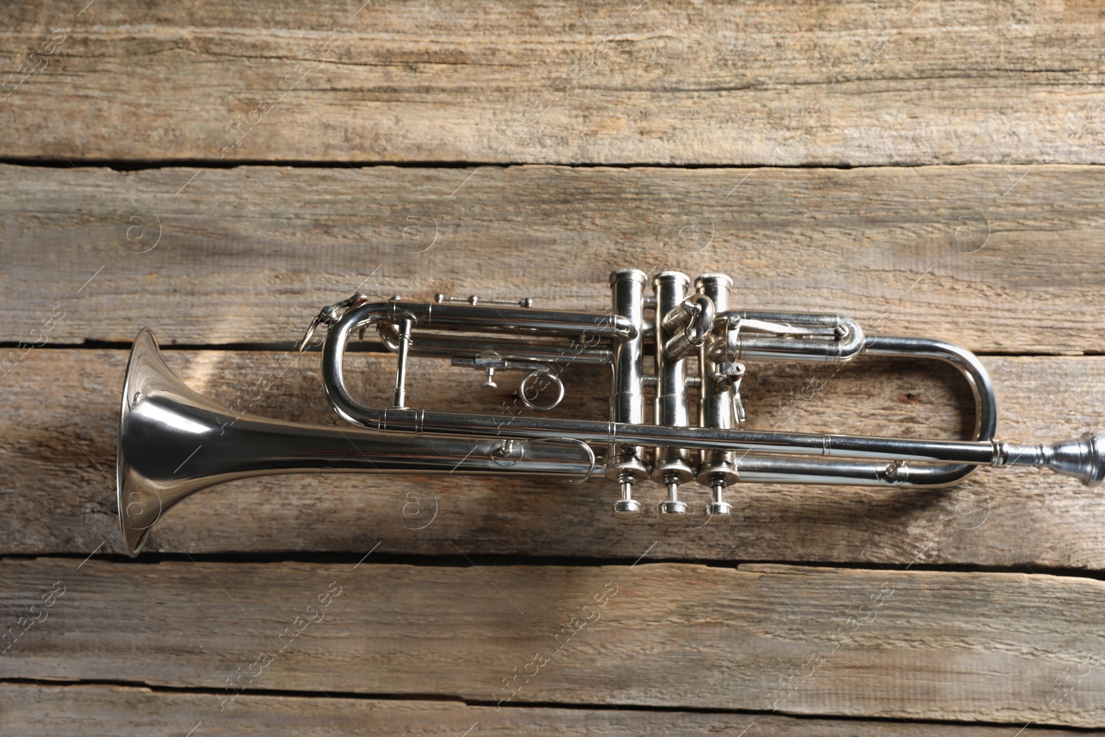 Photo of Trumpet on wooden table, top view. Wind musical instrument