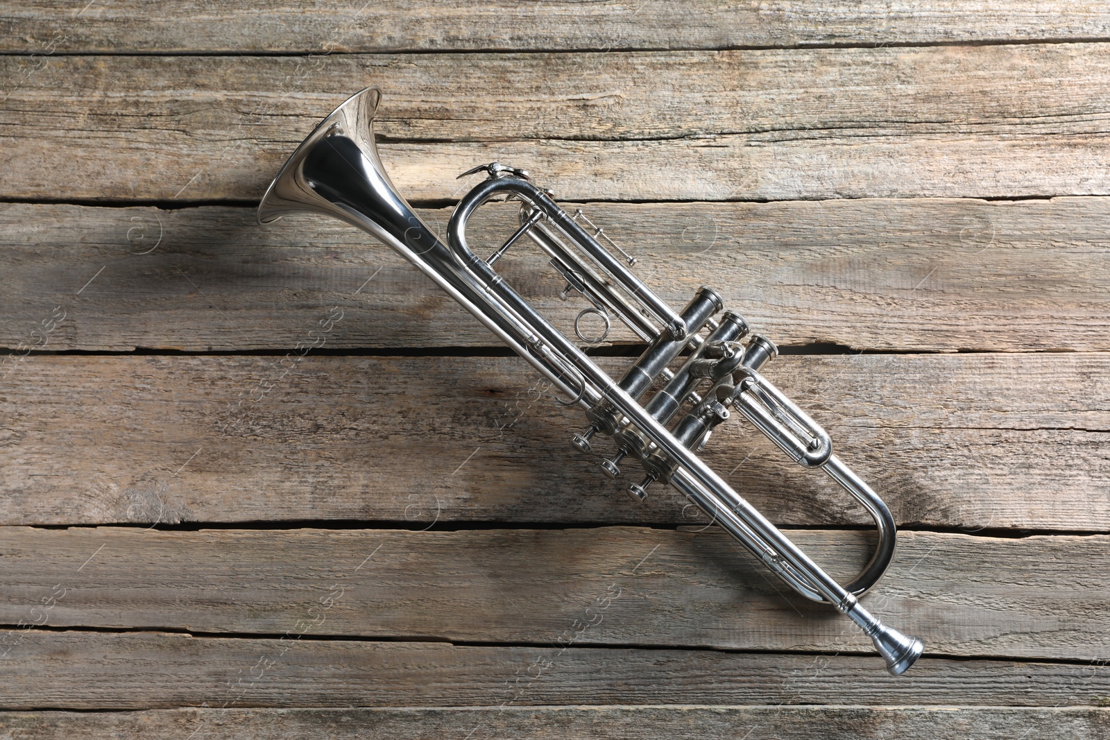 Photo of Trumpet on wooden table, top view. Wind musical instrument