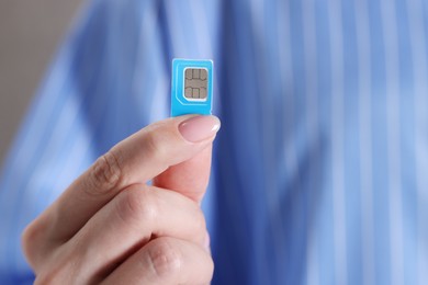 Photo of Woman holding SIM card indoors, closeup view