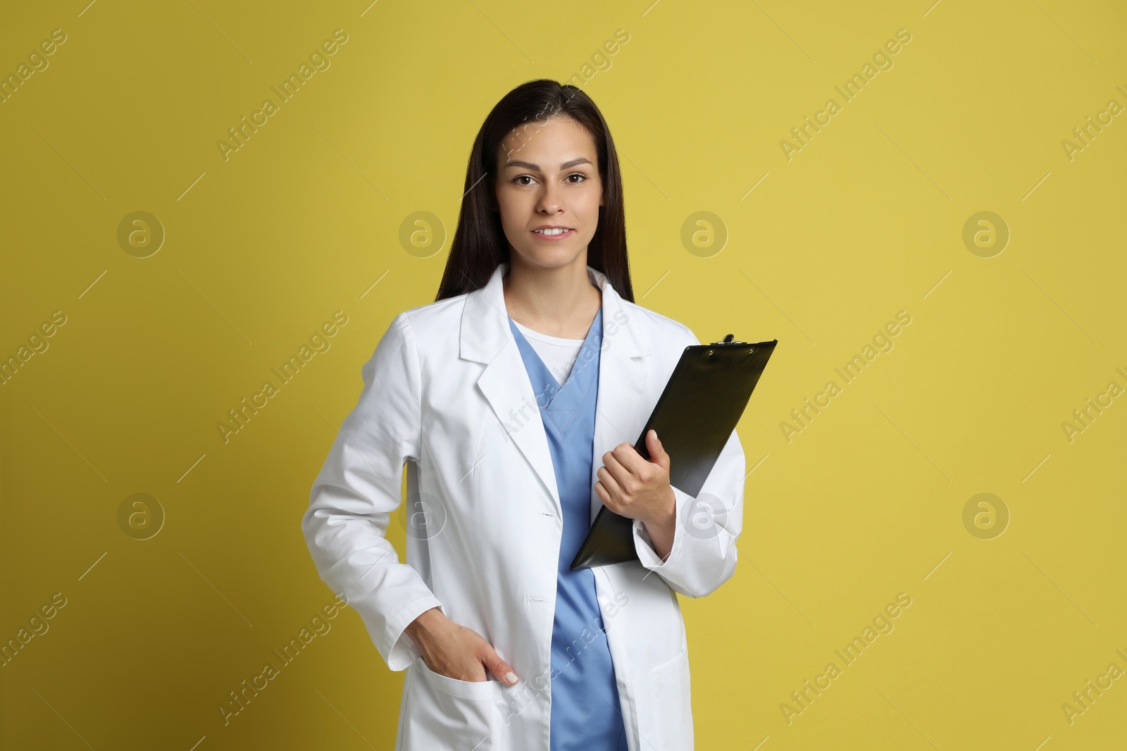 Photo of Portrait of smiling nurse with clipboard on yellow background