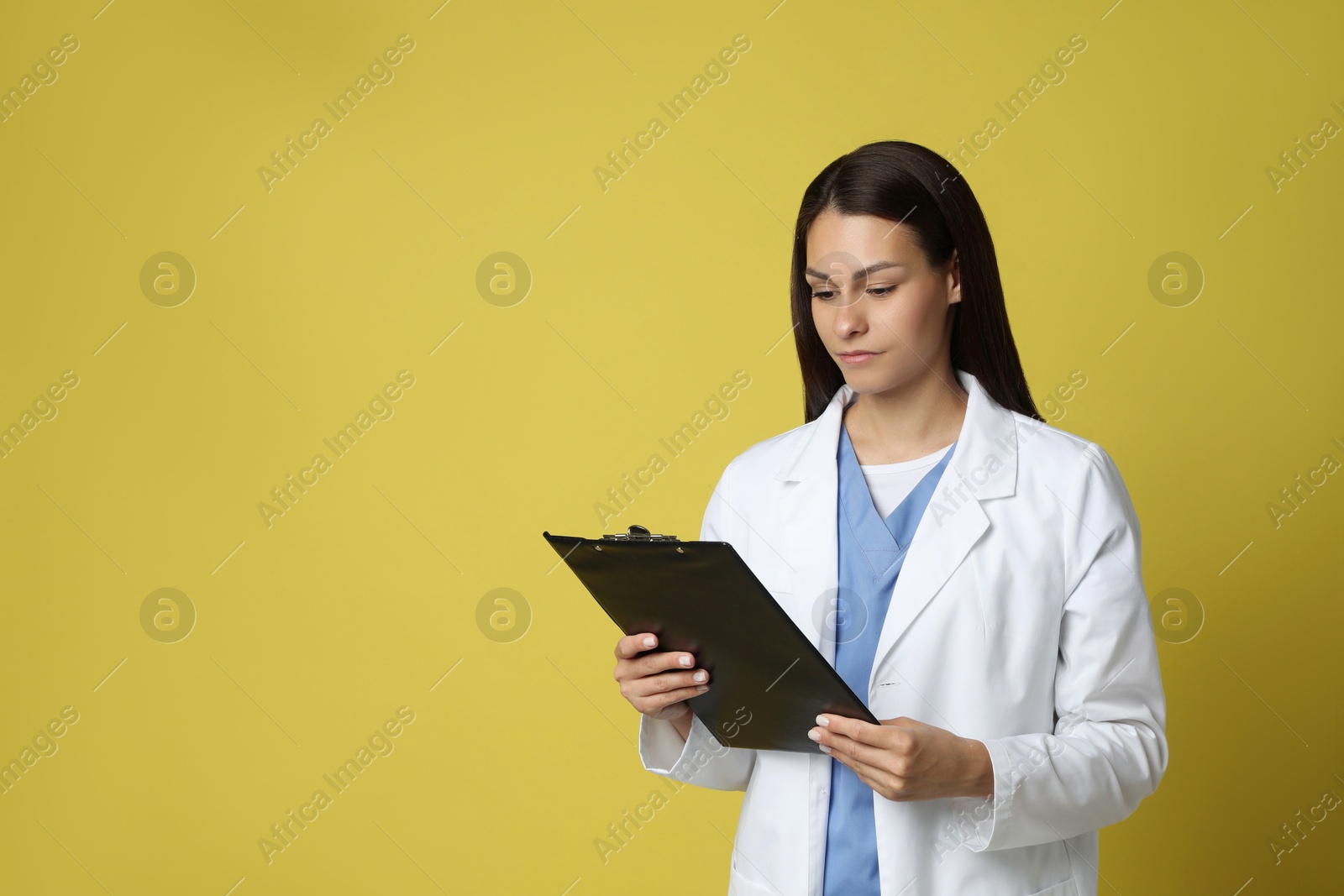 Photo of Portrait of beautiful nurse with clipboard on yellow background. Space for text