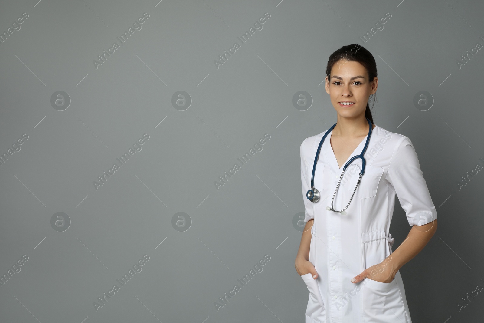 Photo of Portrait of smiling nurse on grey background. Space for text