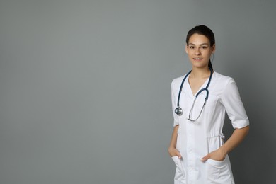 Portrait of smiling nurse on grey background. Space for text