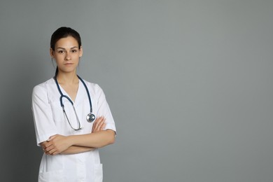 Portrait of beautiful nurse with crossed arms on grey background. Space for text