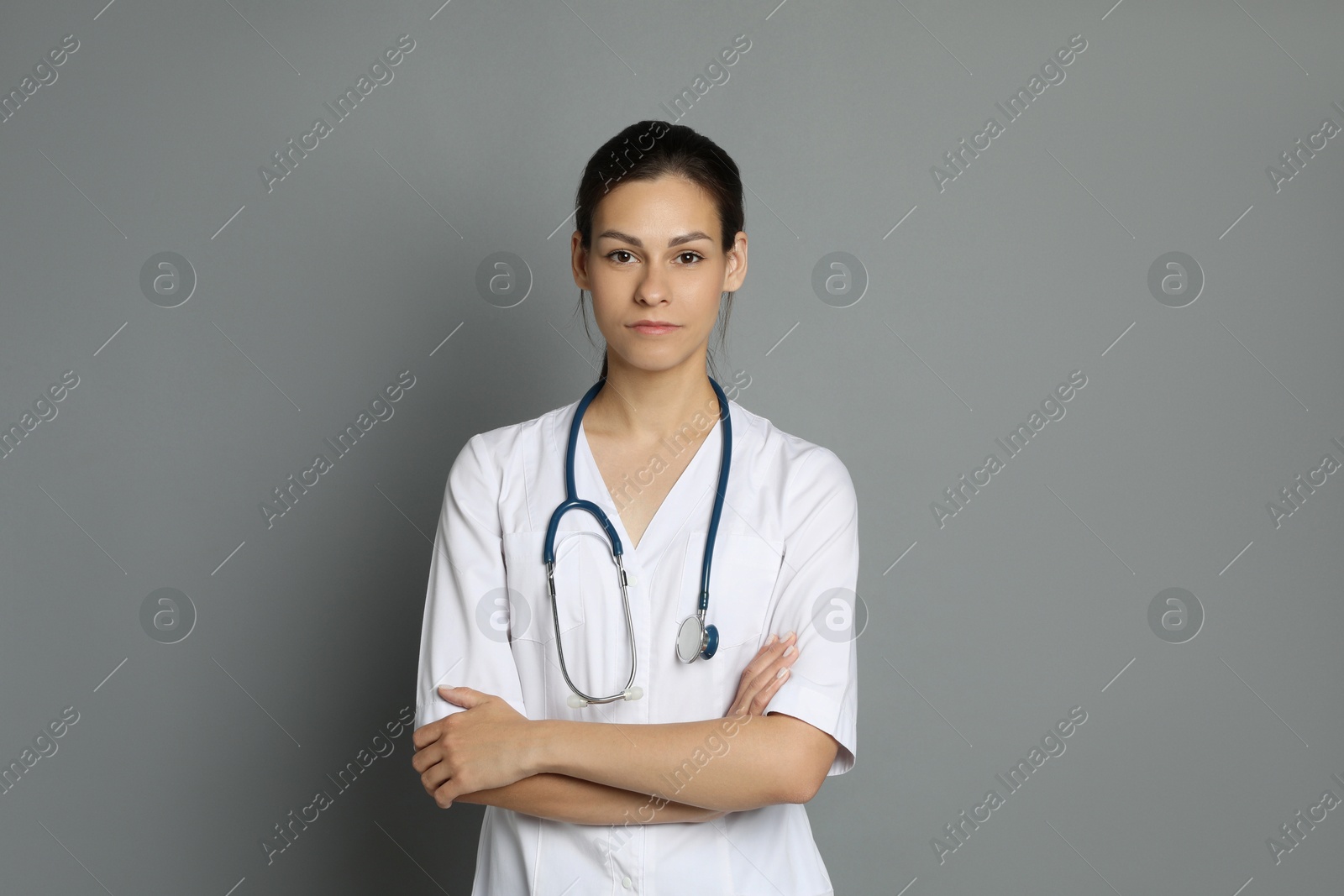 Photo of Portrait of beautiful nurse with crossed arms on grey background