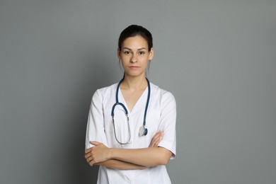 Portrait of beautiful nurse with crossed arms on grey background