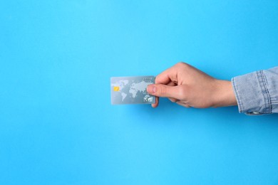 Man holding credit card on light blue background, closeup