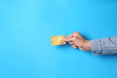 Man holding credit card on light blue background, closeup