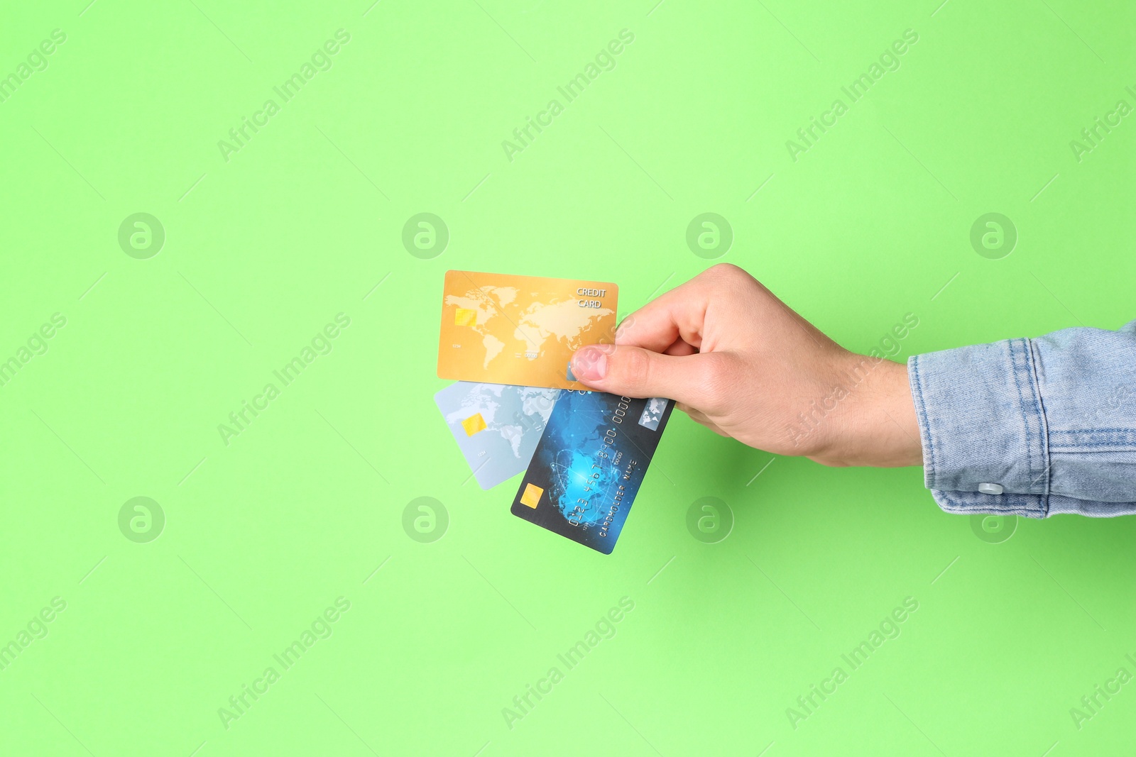 Photo of Man holding credit cards on light green background, closeup