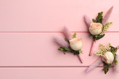 Many small stylish boutonnieres on pink wooden table, flat lay. Space for text