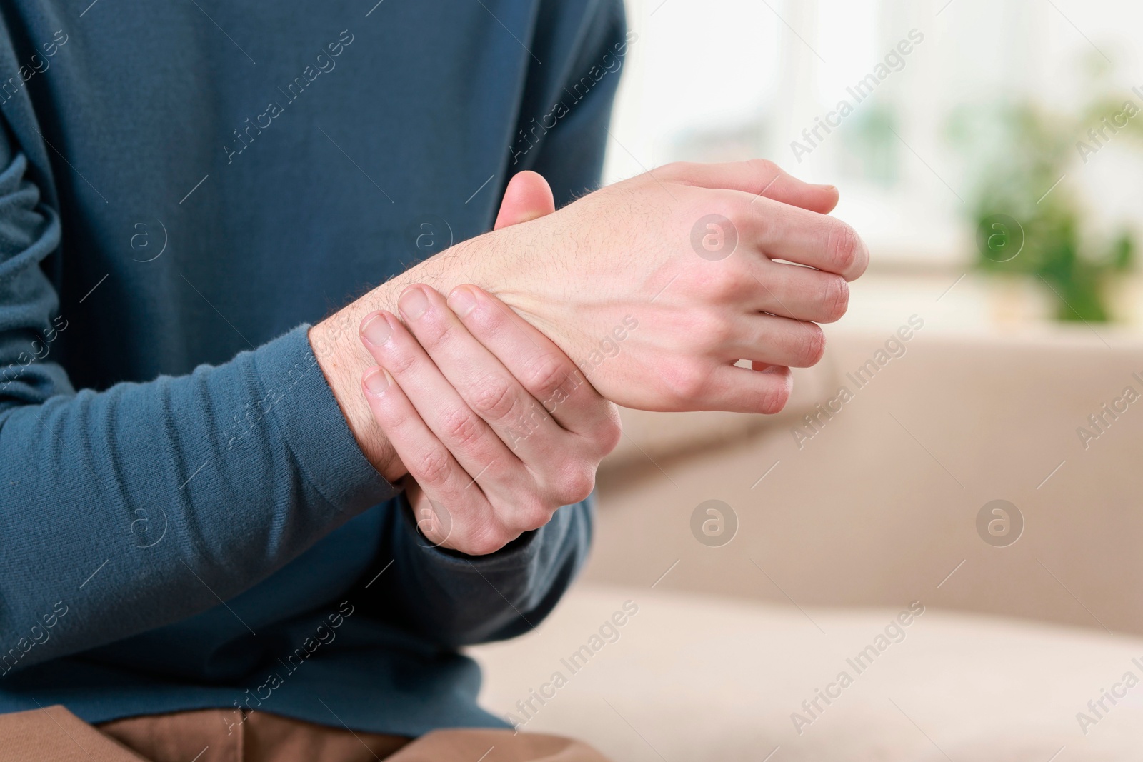 Photo of Man suffering from pain in hand indoors, closeup