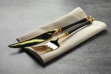 Photo of Elegant golden cutlery and napkin on grey table