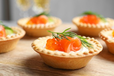 Photo of Delicious canapes with salmon and red caviar on wooden table, closeup