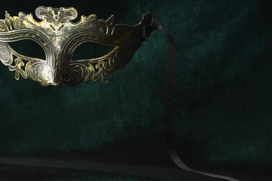 Photo of Theater arts. Venetian carnival mask against green fabric, closeup. Space for text