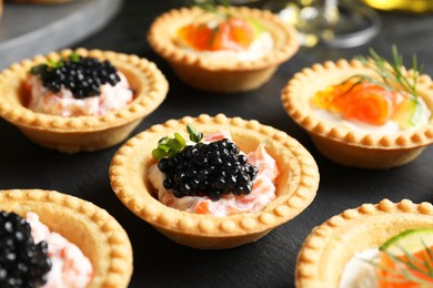 Photo of Delicious canapes with salmon and caviar on black table, closeup