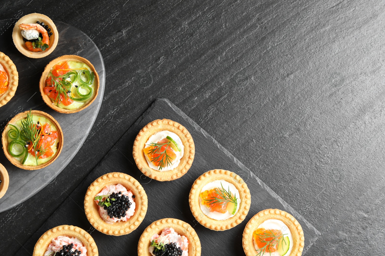 Photo of Delicious canapes with salmon and caviar on black textured table, flat lay. Space for text